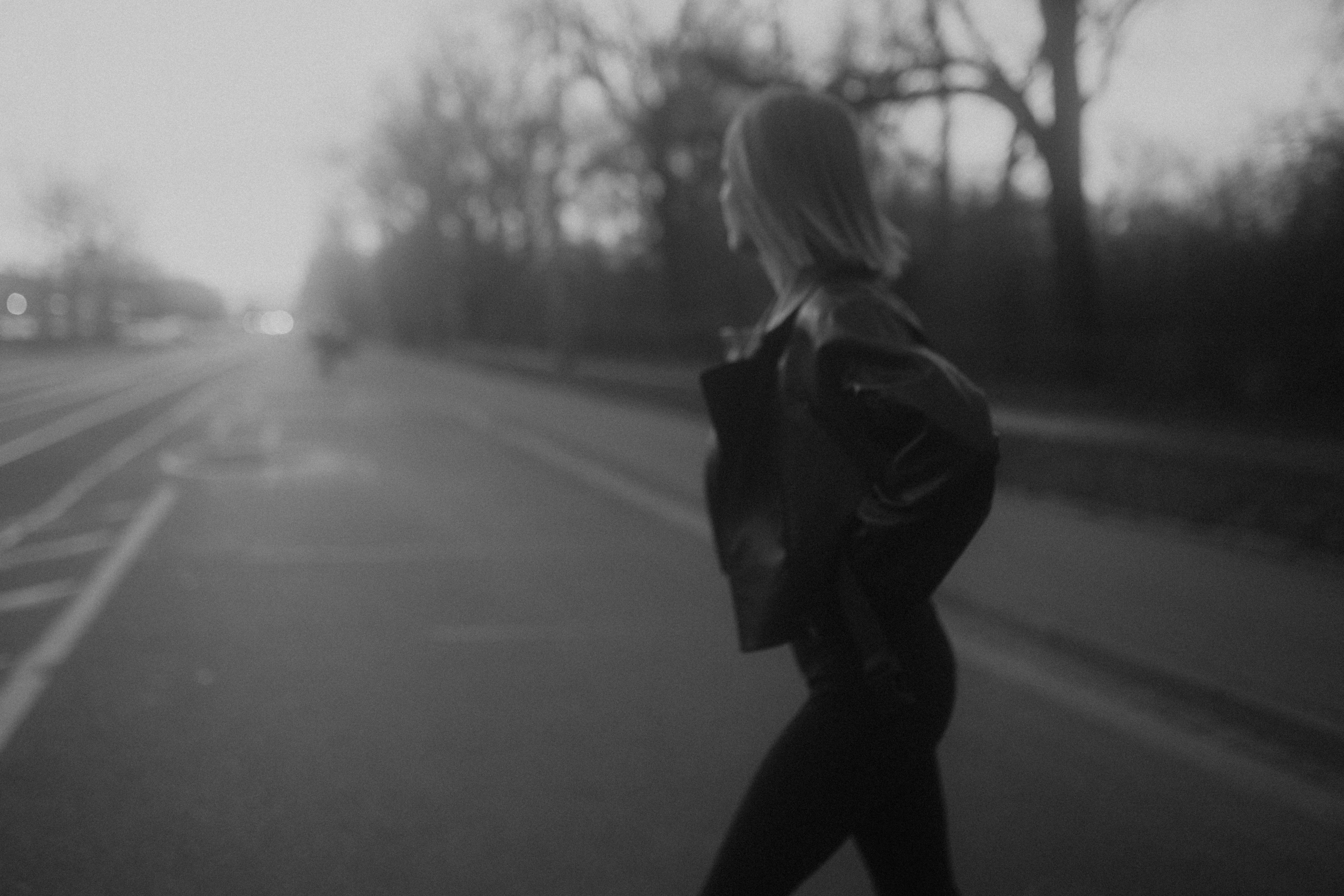 woman in black jacket and pants walking on road during daytime